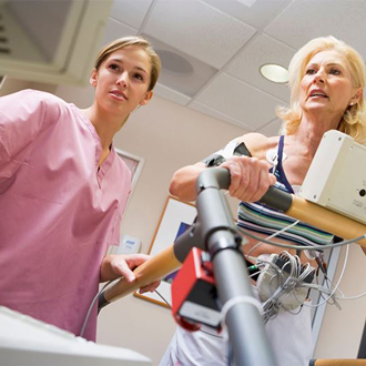 Electrocardiography technician reviews patient's results while patient walks on treadmill
