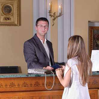 Male hotel front desk manager checks in female guest