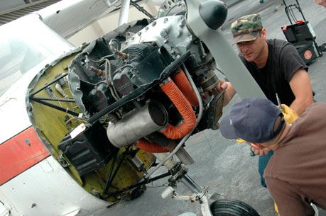 Two male maintenance workers inspect front rotor engine of plane