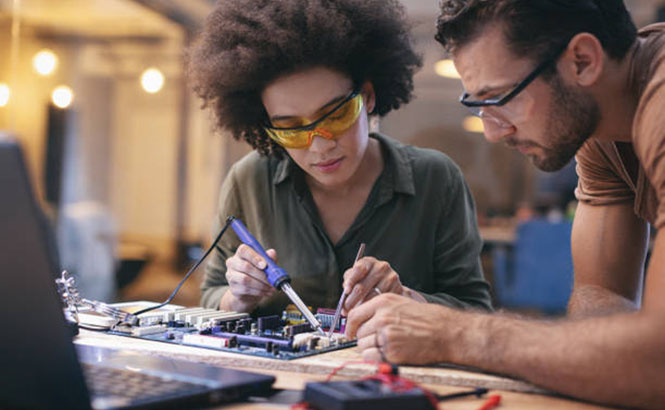 Two students practice on the circuit board