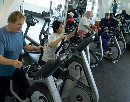 Group of people work out on stationary bikes in a gym