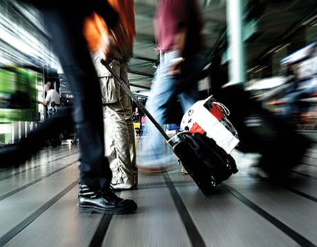 Blurred image of people walking at an airport and their suitcases