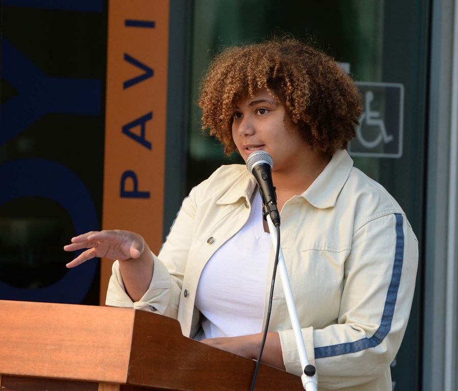 Creative Writing student Jessica Peyton reads her poetry at a podium 