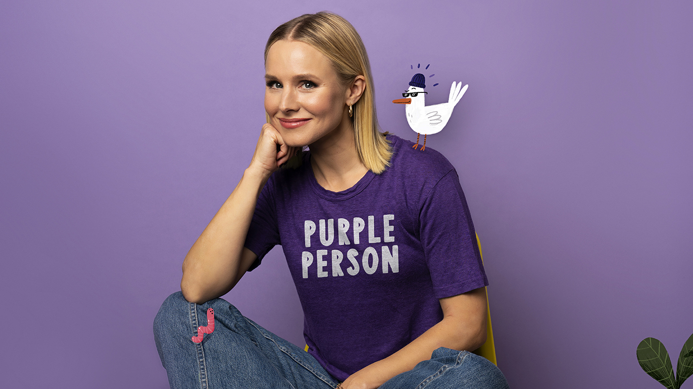 actress kristen bell sitting cross legged against purple backdrop